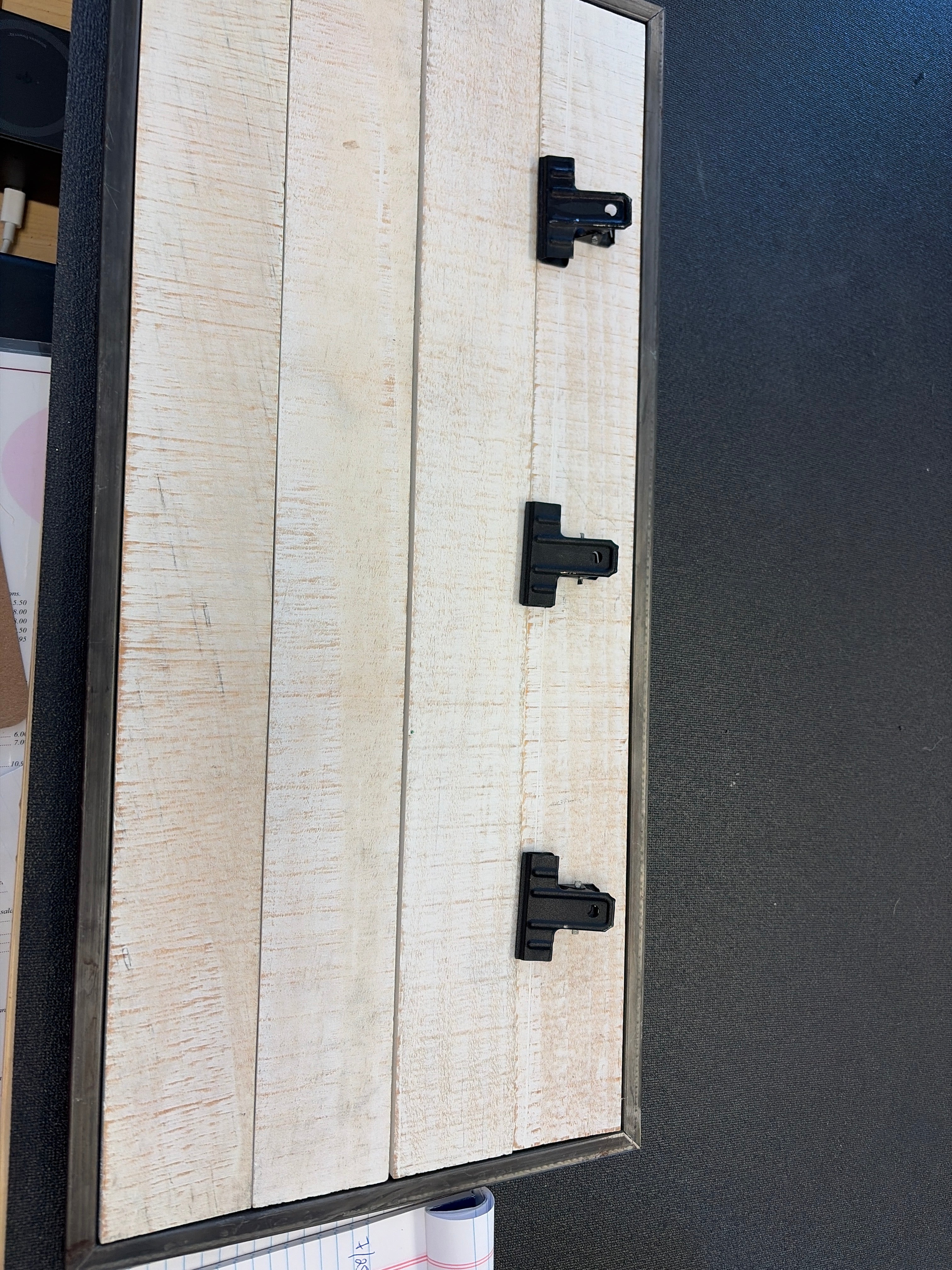 whitewashed wood clipboard wall panel, rustic vertical plank design accented with three attached black metal binder clips and a dark gray metal frame.