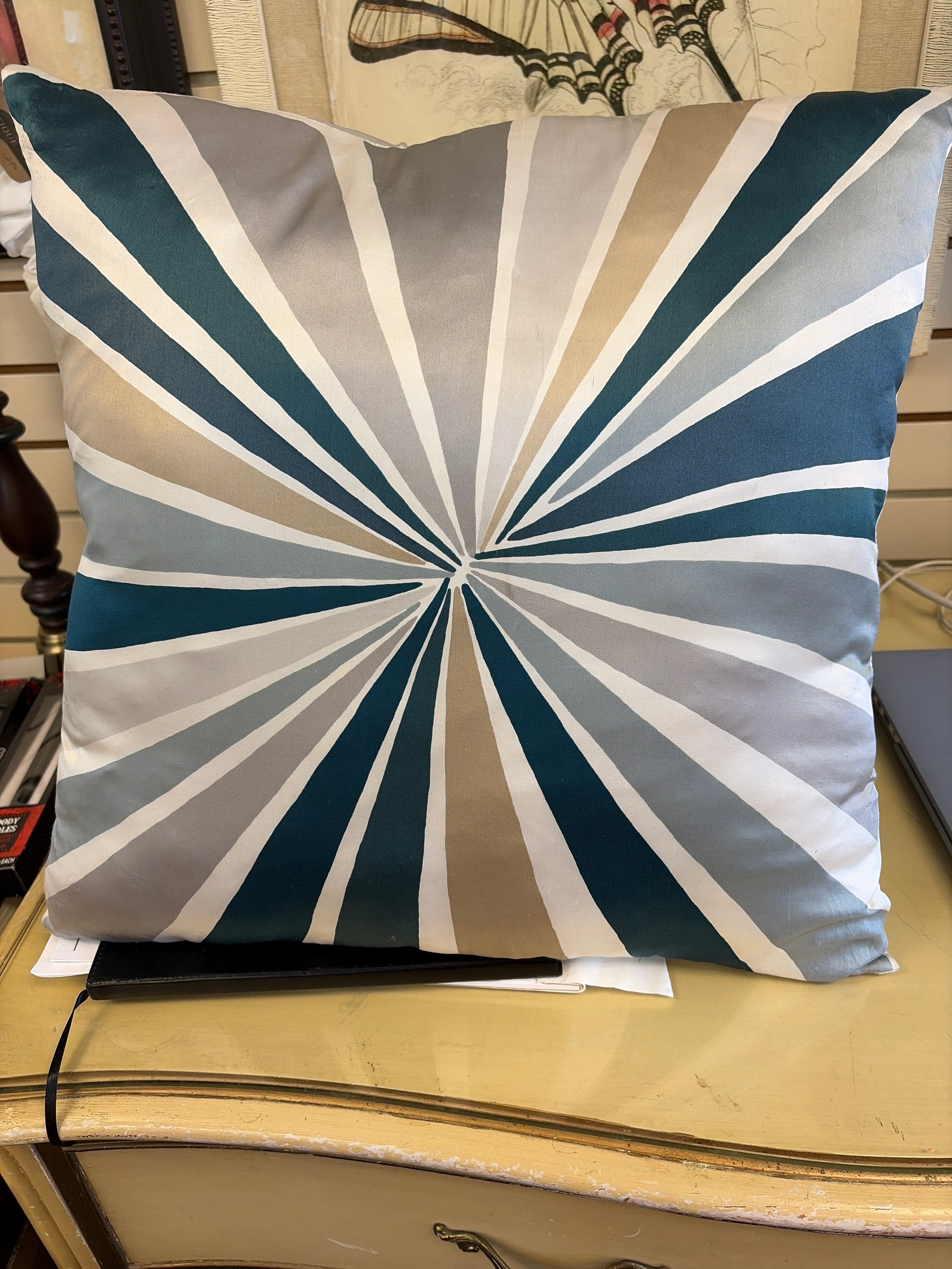 throw pillow striking radial starburst geometric pattern in a palette of teal, beige, grey, and white.