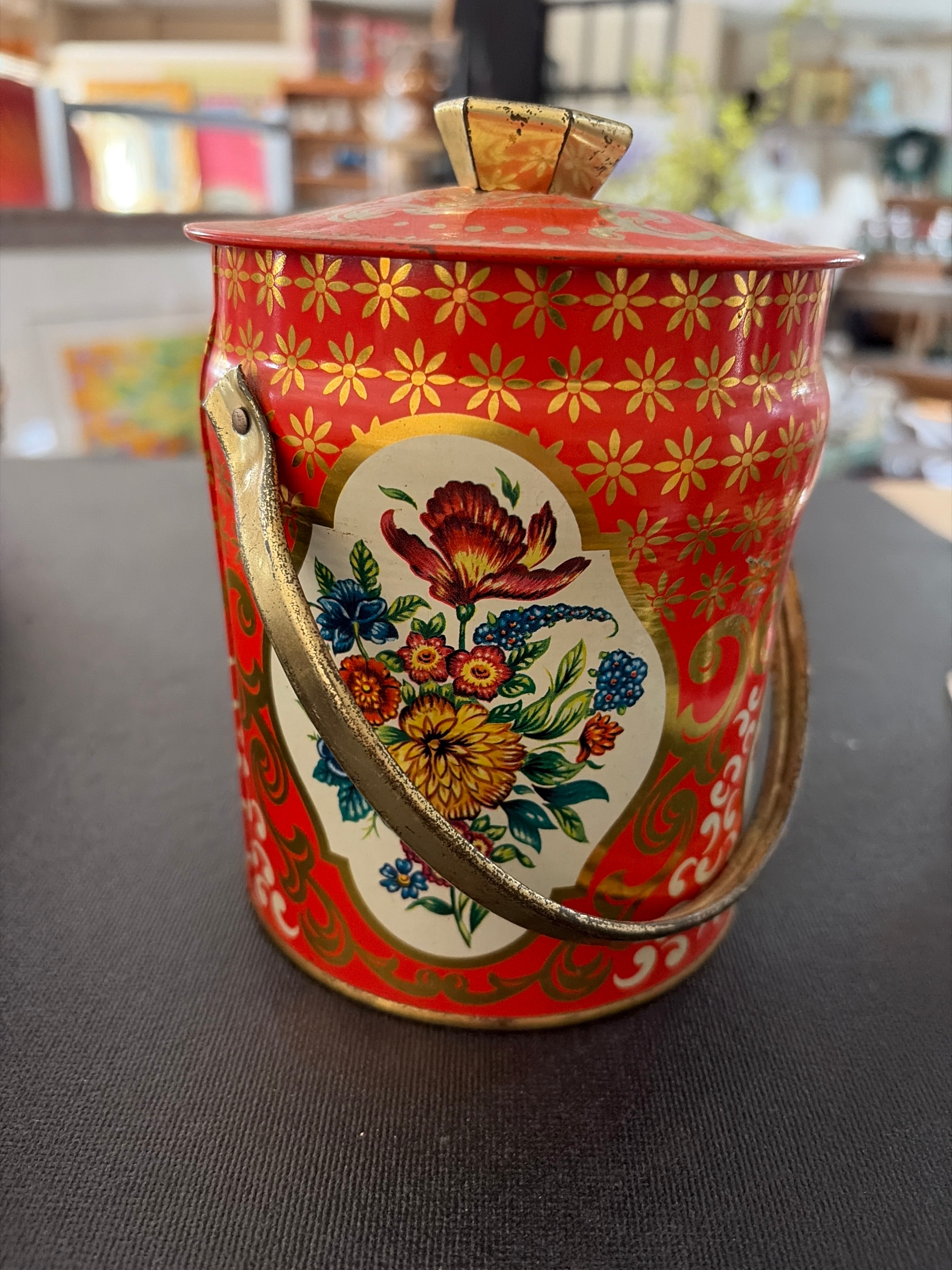Vintage Murray Allen Confections tin with a red floral design, handle, and gold lid knob