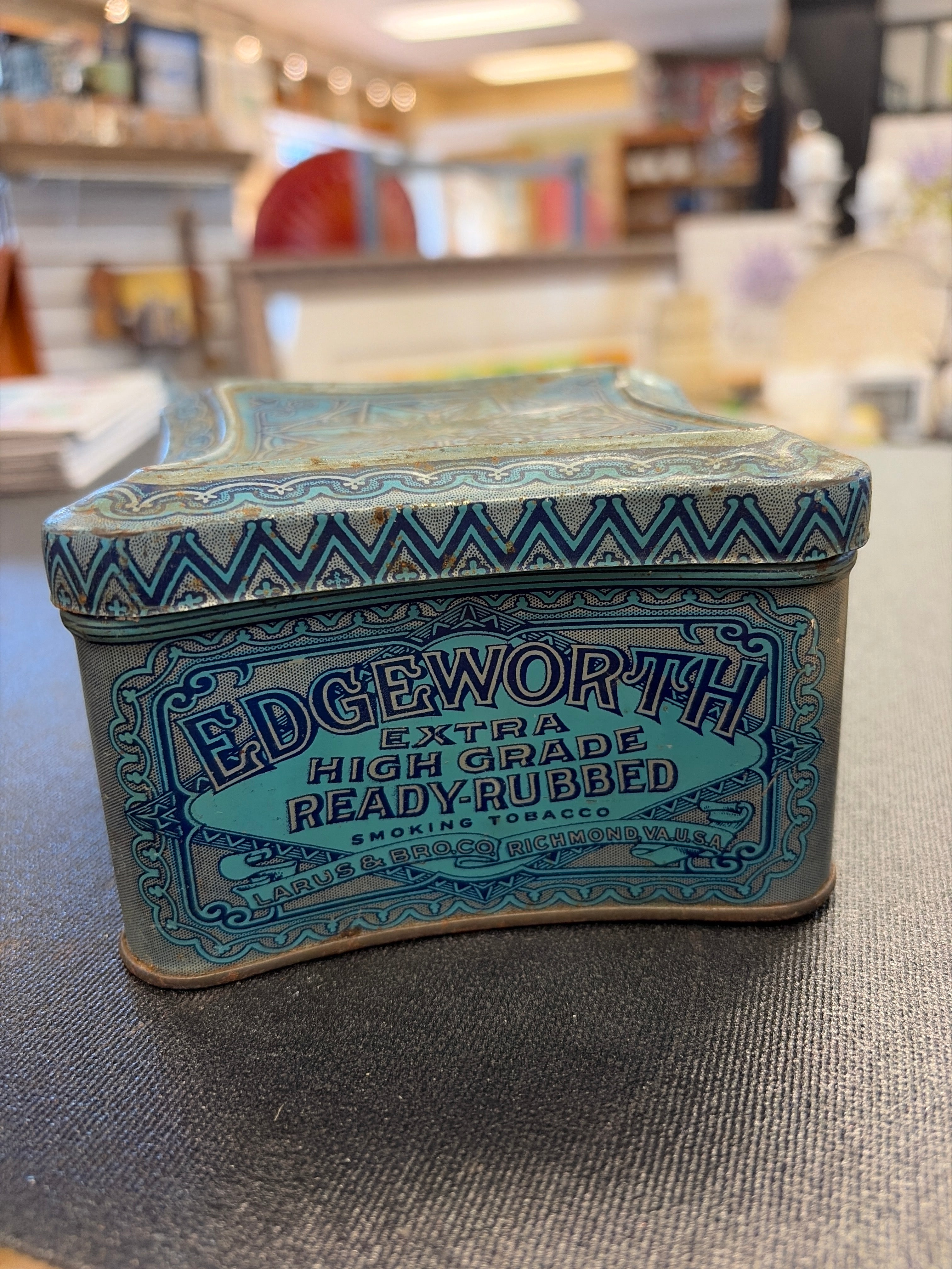 Vintage Edgeworth smoking tobacco tin with distinctive blue art deco graphics and concave, pinched sides