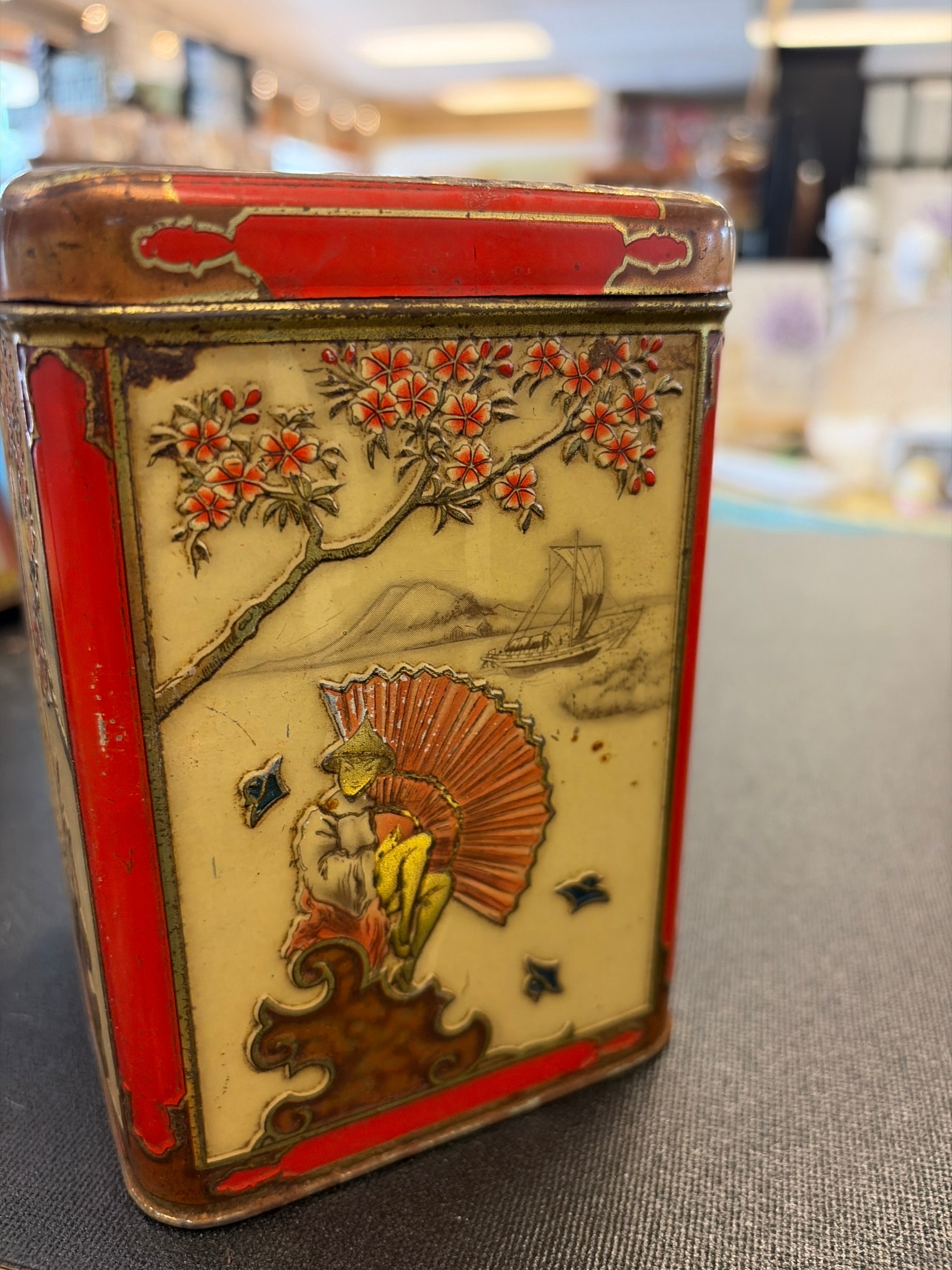 Vintage 1930s Niemeyer Oriental tea tin from Holland featuring embossed Japanese-themed scenes in red, cream, and gold colors